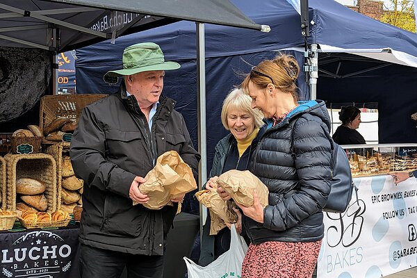 Paul Arnott with Lib Dem campaigners Dianne Conduit and Trudi Cotton, holding freshly-baked sourdough bread bought from a local business exhibiting at the Exmouth Gate to Plate Festival